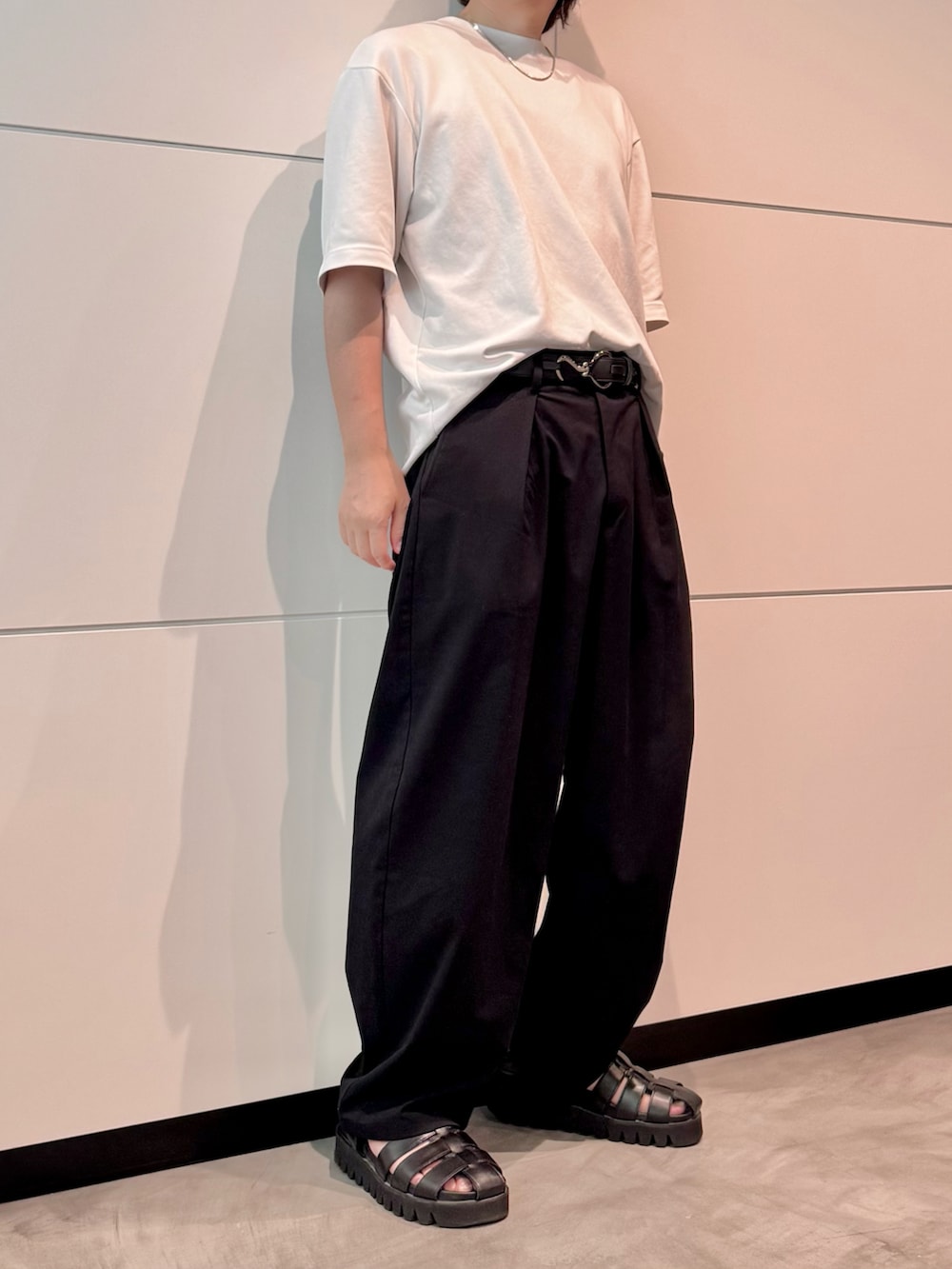 ホワイト系のTシャツ/カットソー、ブラック系のスラックス、ブラック系のサンダルを着用したメンズの夏コーディネートの2枚目の写真