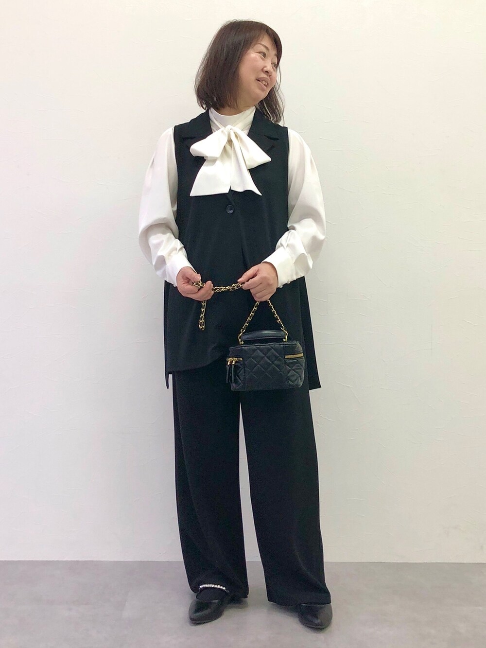 ホワイト系のニット/セーター、ブラック系のスーツセットを着用したレディースの冬コーディネートの2枚目の写真