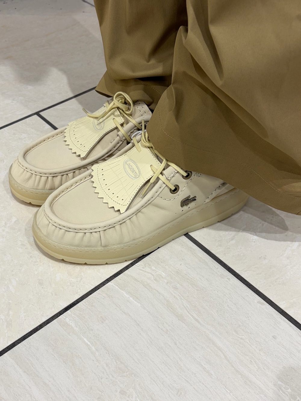 ベージュ系のトートバッグ、ベージュ系のシューズ、イエロー系のニット/セーターを着用したレディースの春コーディネートの5枚目の写真