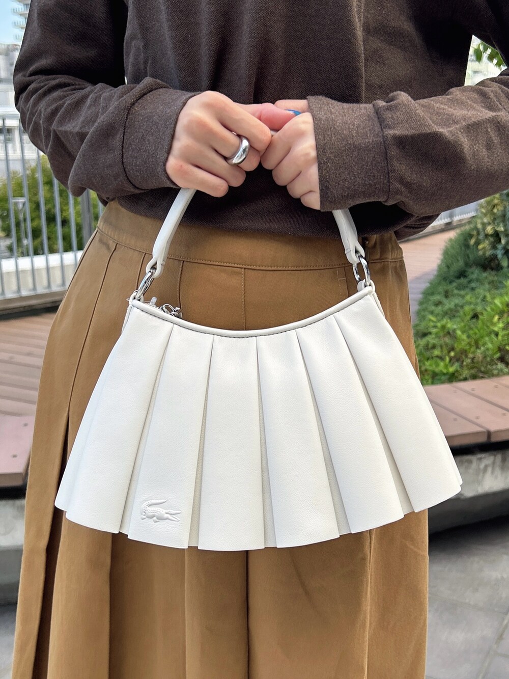 グリーン系のポロシャツ、イエロー系のスカート、グリーン系のショルダーバッグを着用したレディースの秋コーディネートの4枚目の写真
