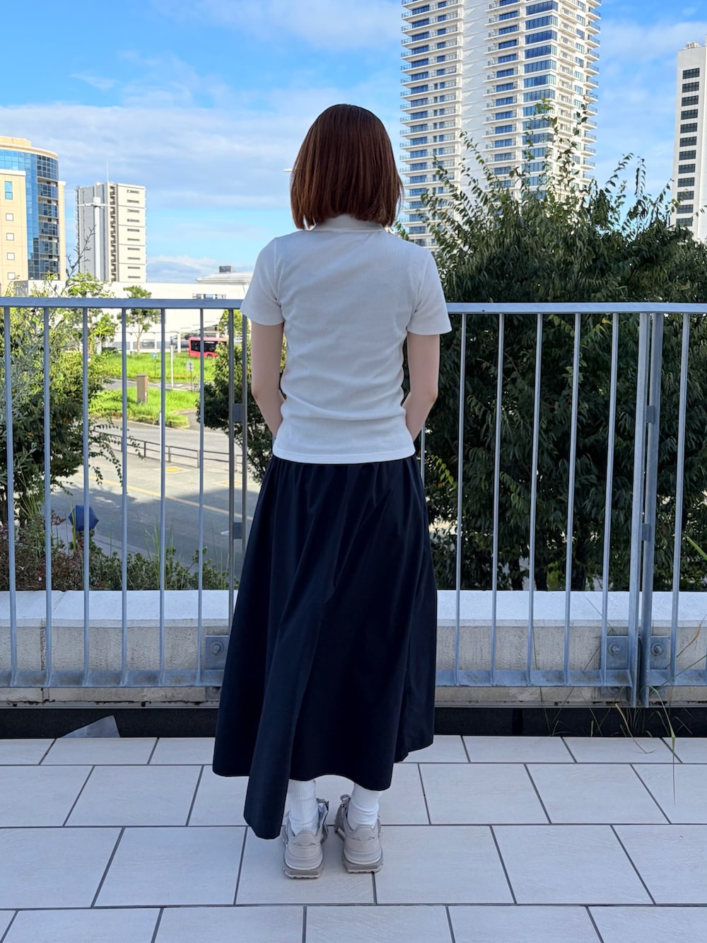 ホワイト系のポロシャツ、ブルー系のスカート、ピンク系のトートバッグを着用したレディースの夏コーディネートの2枚目の写真