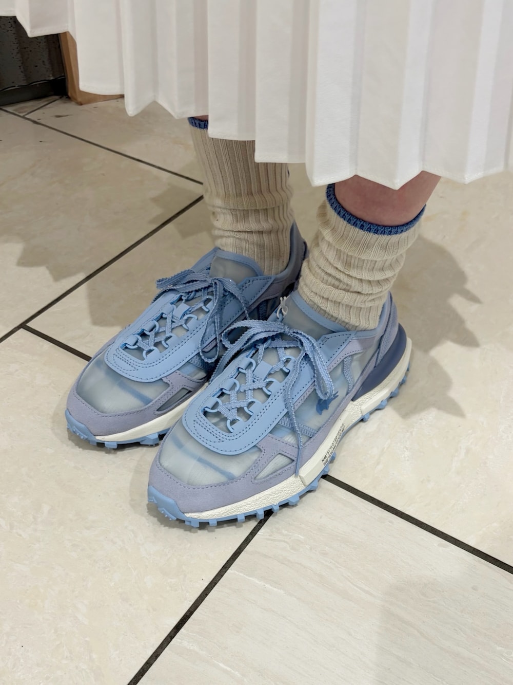 ブルー系のポロシャツ、ホワイト系のカーディガン/ボレロ、シルバー系のバッグを着用したレディースの春コーディネートの5枚目の写真