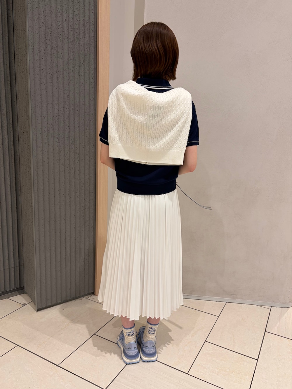 ブルー系のポロシャツ、ホワイト系のカーディガン/ボレロ、シルバー系のバッグを着用したレディースの春コーディネートの2枚目の写真
