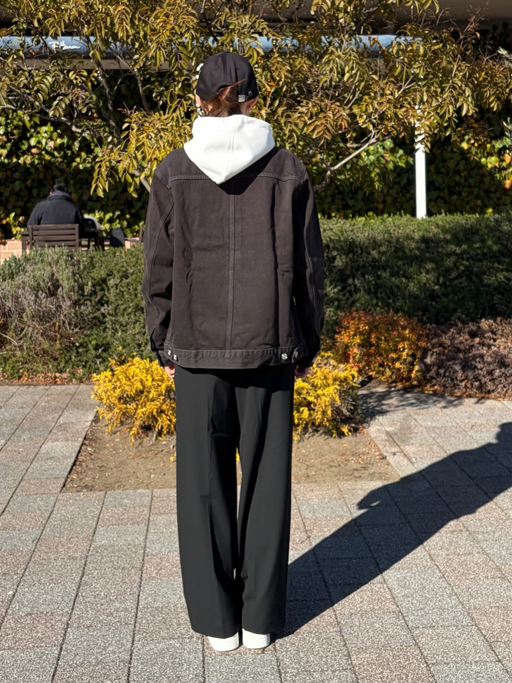 ブラック系のデニムジャケット、ホワイト系のパーカー、ホワイト系のスニーカーを着用したレディースの冬コーディネートの2枚目の写真