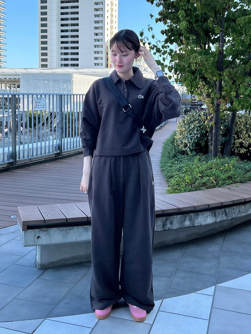 ブラック系のショルダーバッグ、ピンク系のスニーカー、ブラウン系のスウェットを着用したレディースの秋コーディネートの2枚目の写真