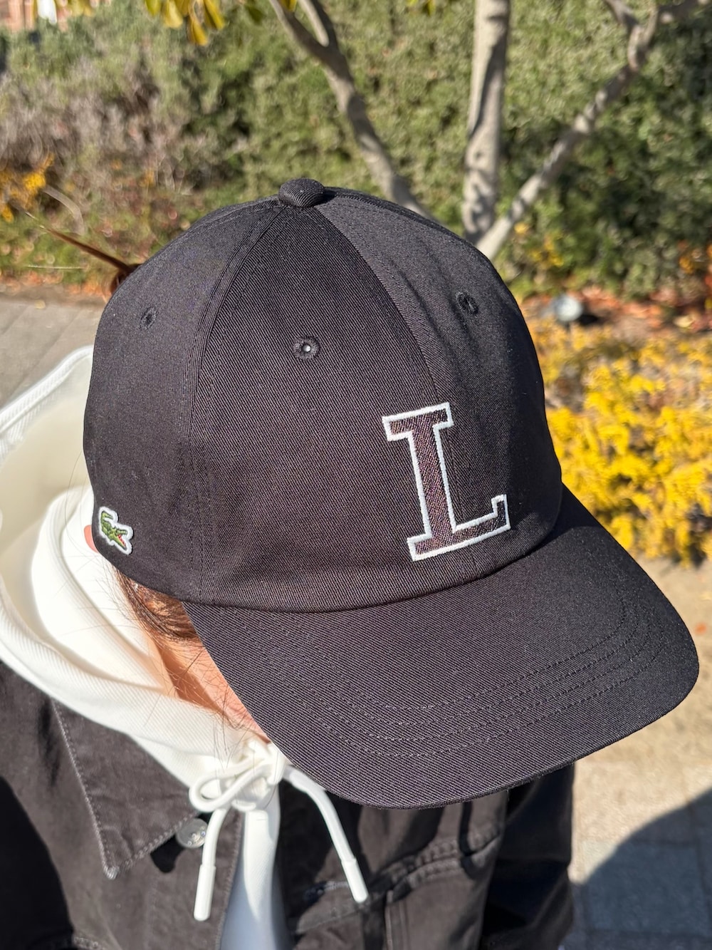 ブラック系のデニムジャケット、ホワイト系のパーカー、ホワイト系のスニーカーを着用したレディースの冬コーディネートの5枚目の写真