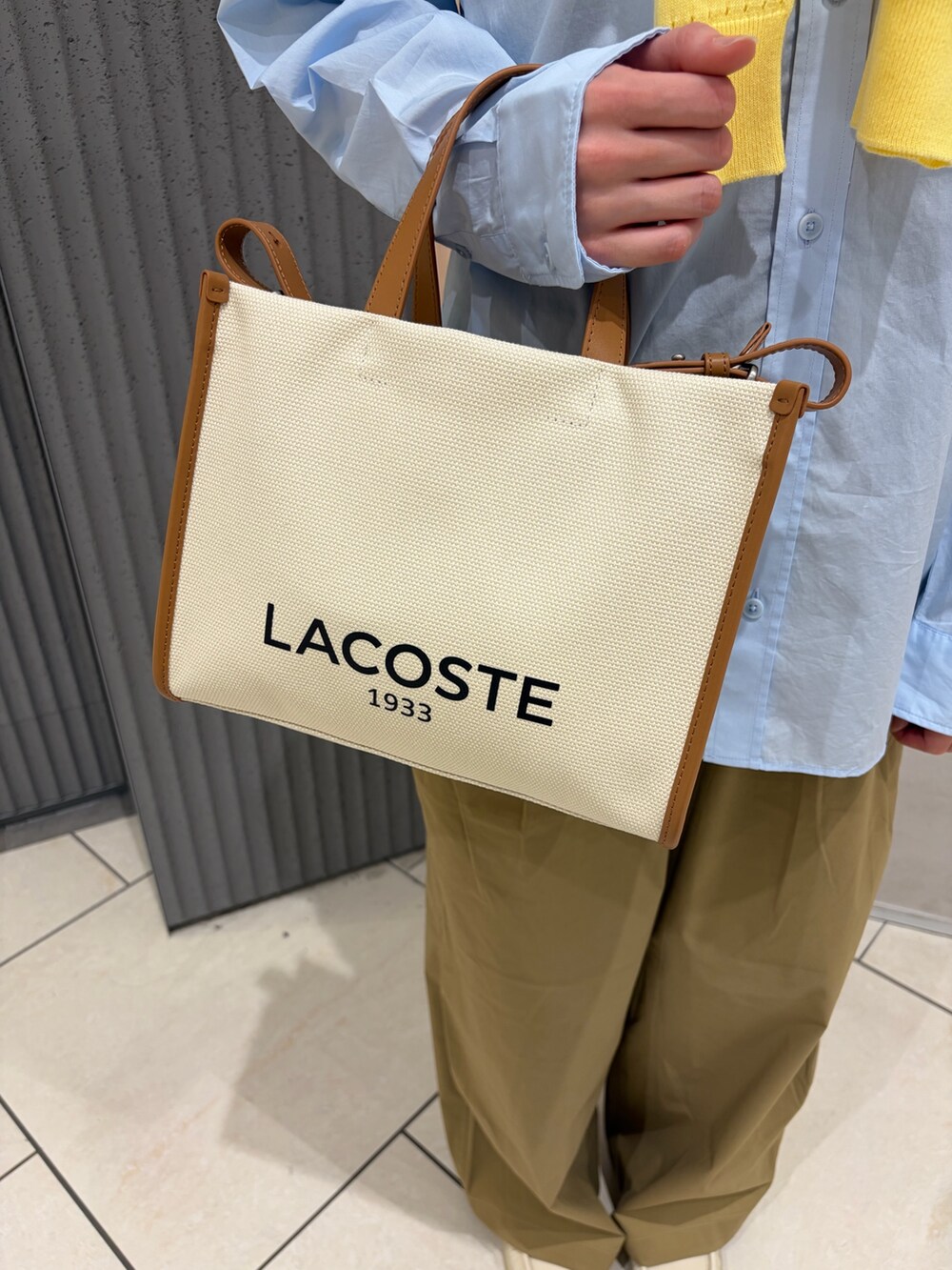 ベージュ系のトートバッグ、ベージュ系のシューズ、イエロー系のニット/セーターを着用したレディースの春コーディネートの4枚目の写真