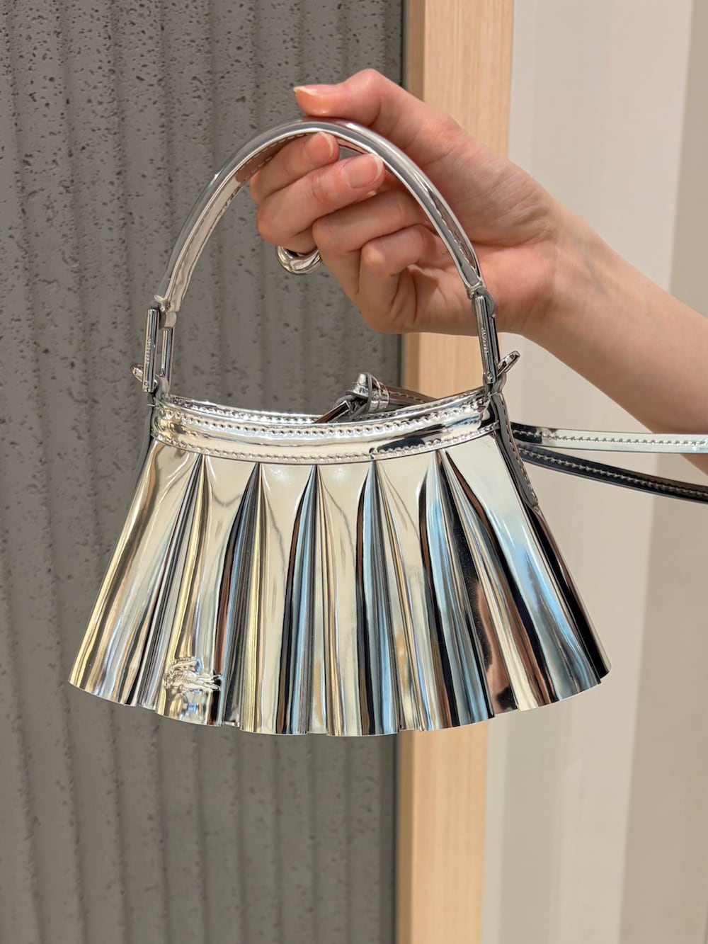 ブルー系のポロシャツ、ホワイト系のカーディガン/ボレロ、シルバー系のバッグを着用したレディースの春コーディネートの4枚目の写真