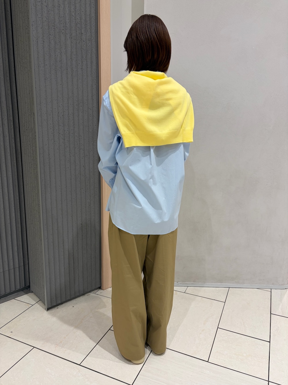 ベージュ系のトートバッグ、ベージュ系のシューズ、イエロー系のニット/セーターを着用したレディースの春コーディネートの2枚目の写真