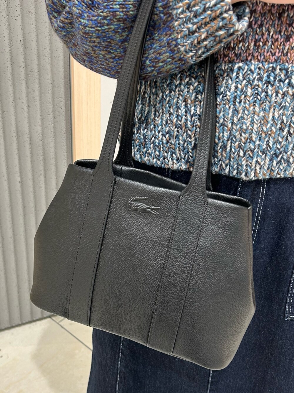 その他のニット/セーター、ブルー系のデニムスカート、ブラック系のトートバッグを着用したレディースの冬コーディネートの4枚目の写真