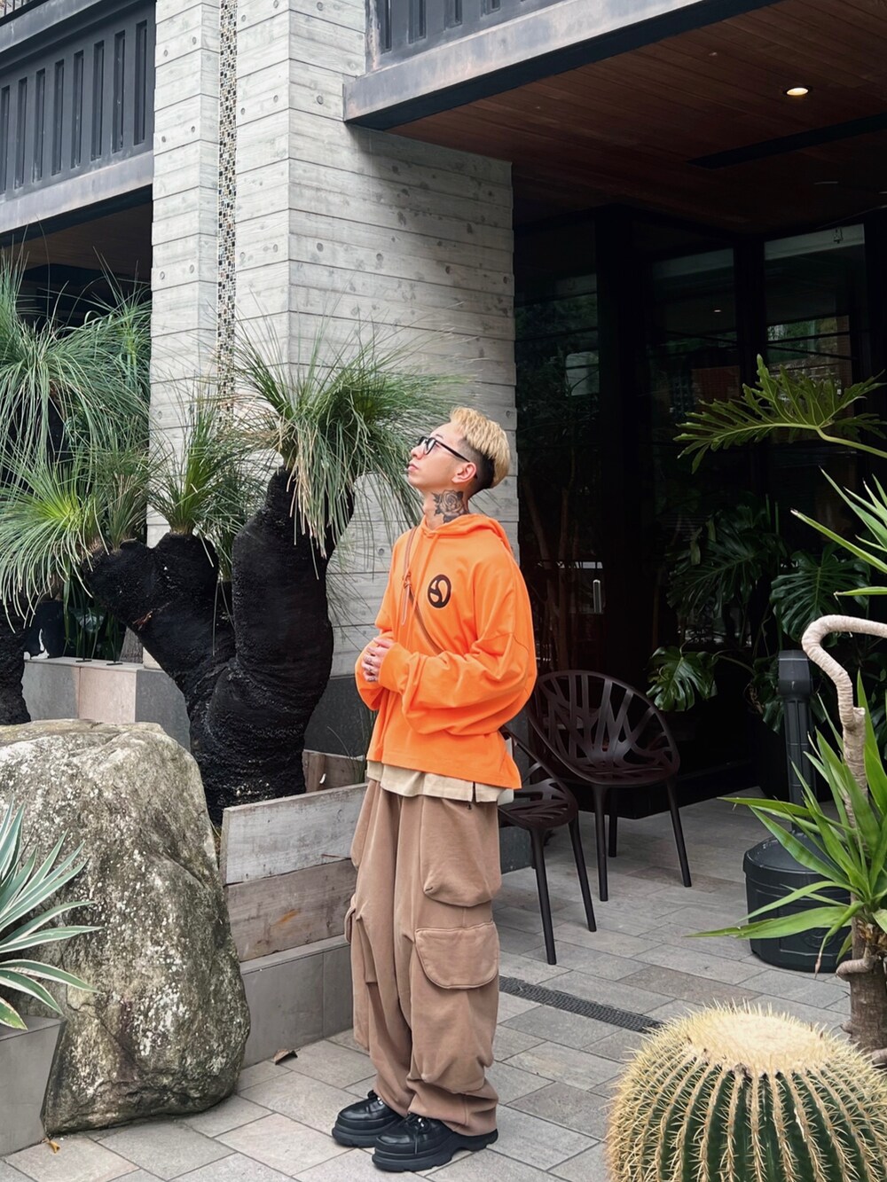 オレンジ系のパーカー、ブラウン系のカーゴパンツを着用したメンズの春コーディネートの2枚目の写真