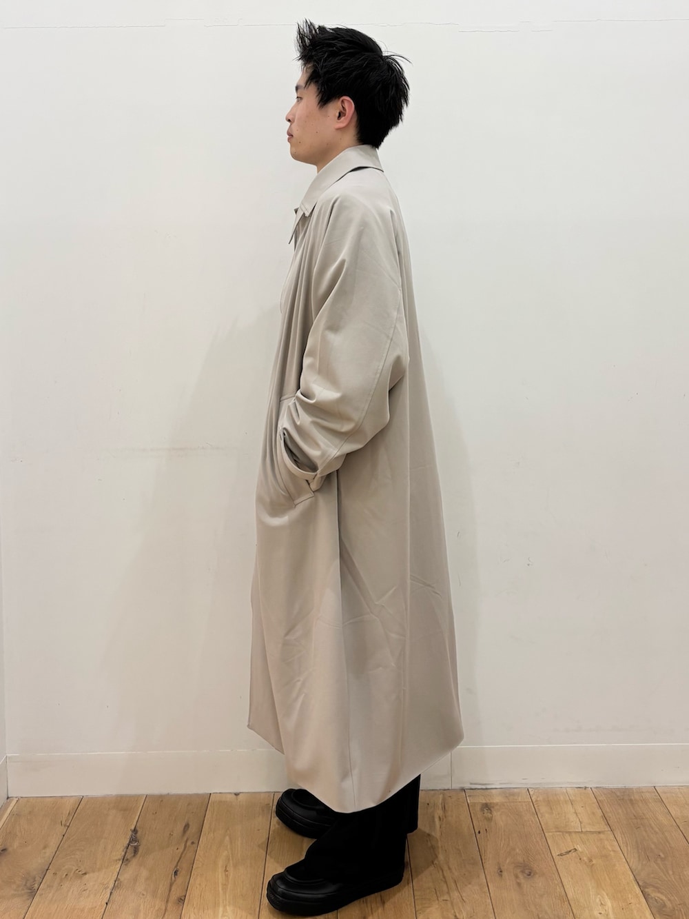 グレー系のTシャツ/カットソー、ブラック系のその他パンツ、ベージュ系のステンカラーコートを着用したメンズの冬コーディネートの2枚目の写真