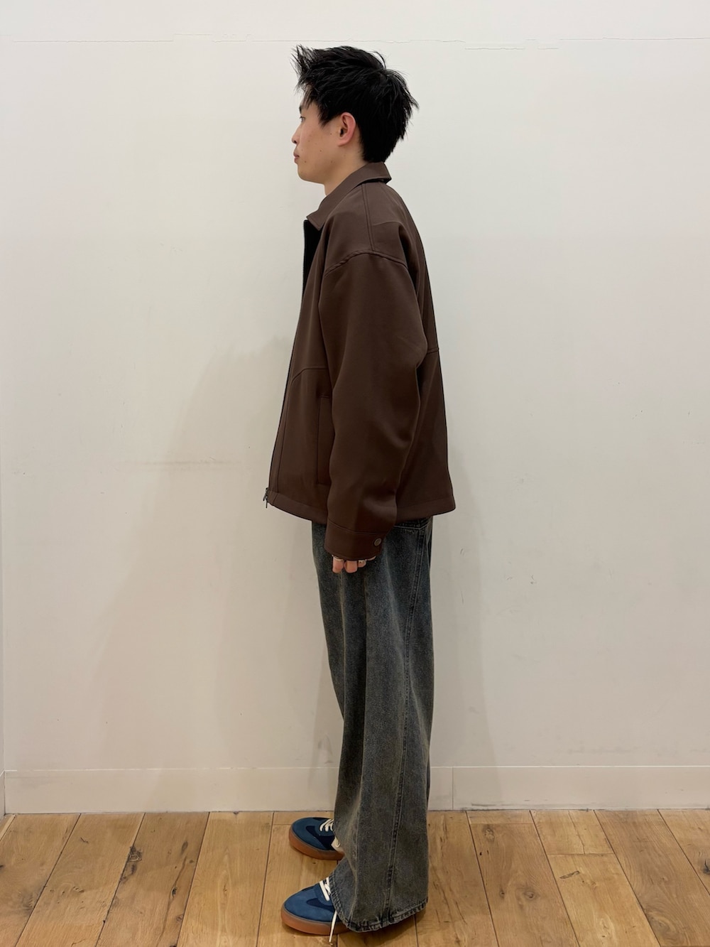 グレー系のスウェット、ブラウン系のブルゾン、ブルー系のデニムパンツを着用したメンズの冬コーディネートの2枚目の写真