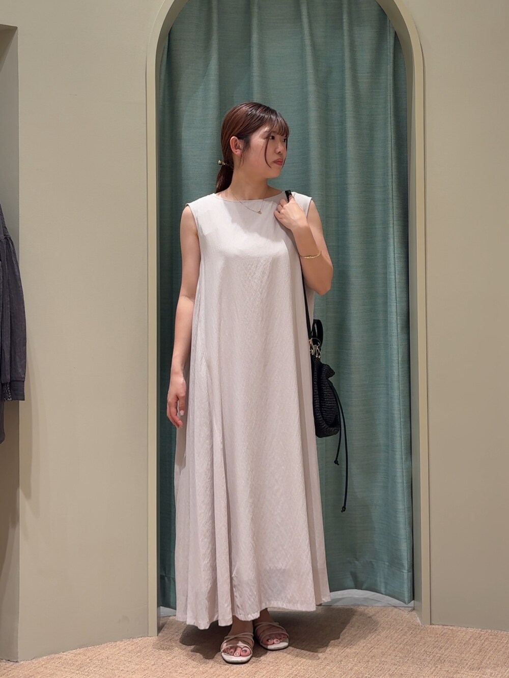 ベージュ系のサンダル、ブラック系のトートバッグ、ホワイト系のワンピースを着用したレディースの夏コーディネートの2枚目の写真