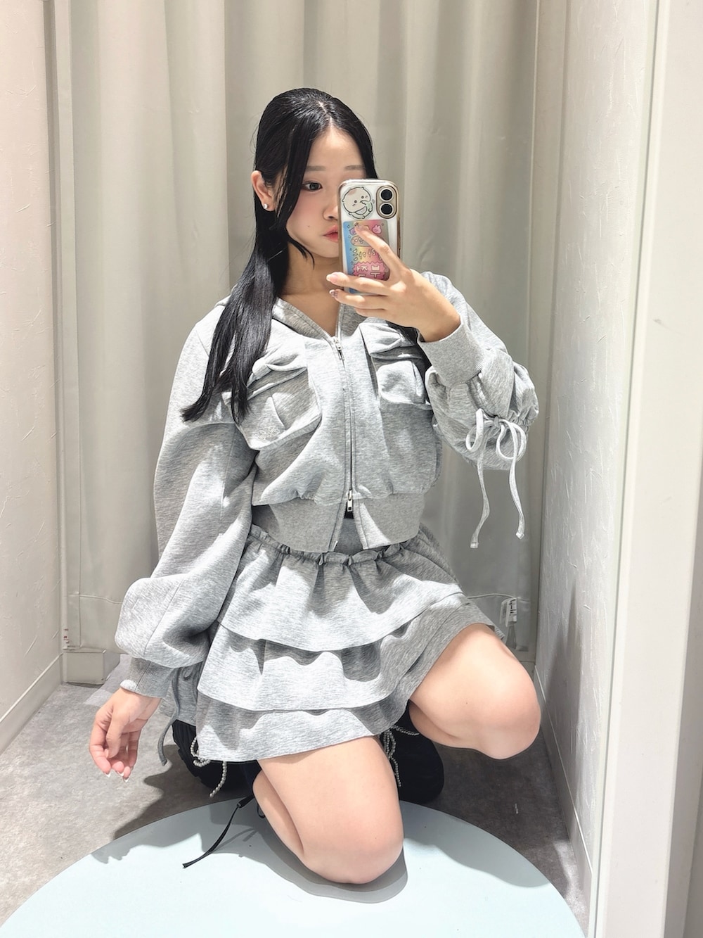 グレー系のスカート、グレー系のパーカー、ブラック系のスニーカーを着用したレディースの春コーディネートの2枚目の写真