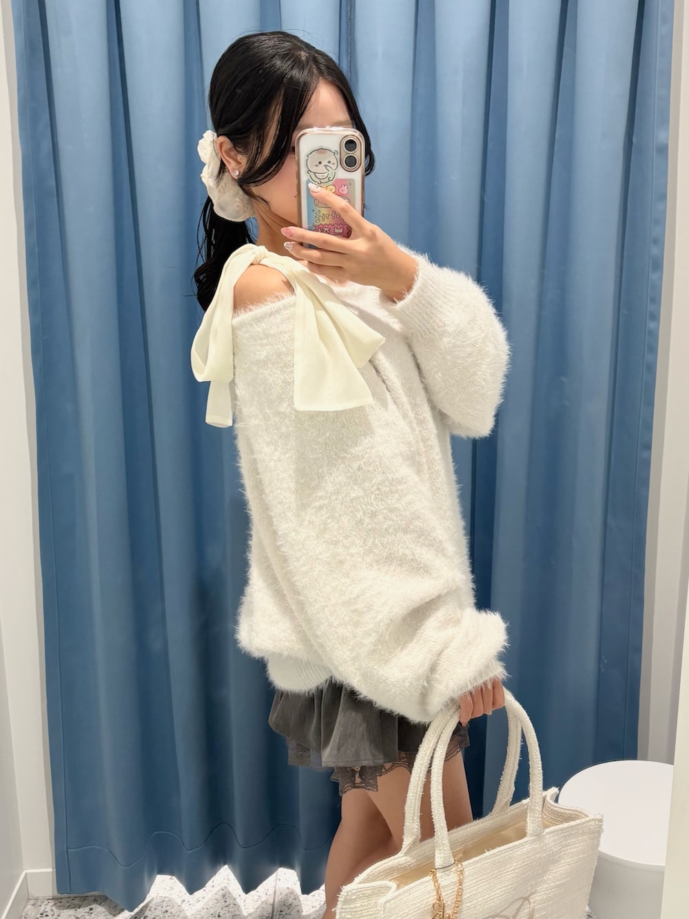 ホワイト系のワンピース、グレー系のスカート、ホワイト系のトートバッグを着用したレディースの冬コーディネートの3枚目の写真