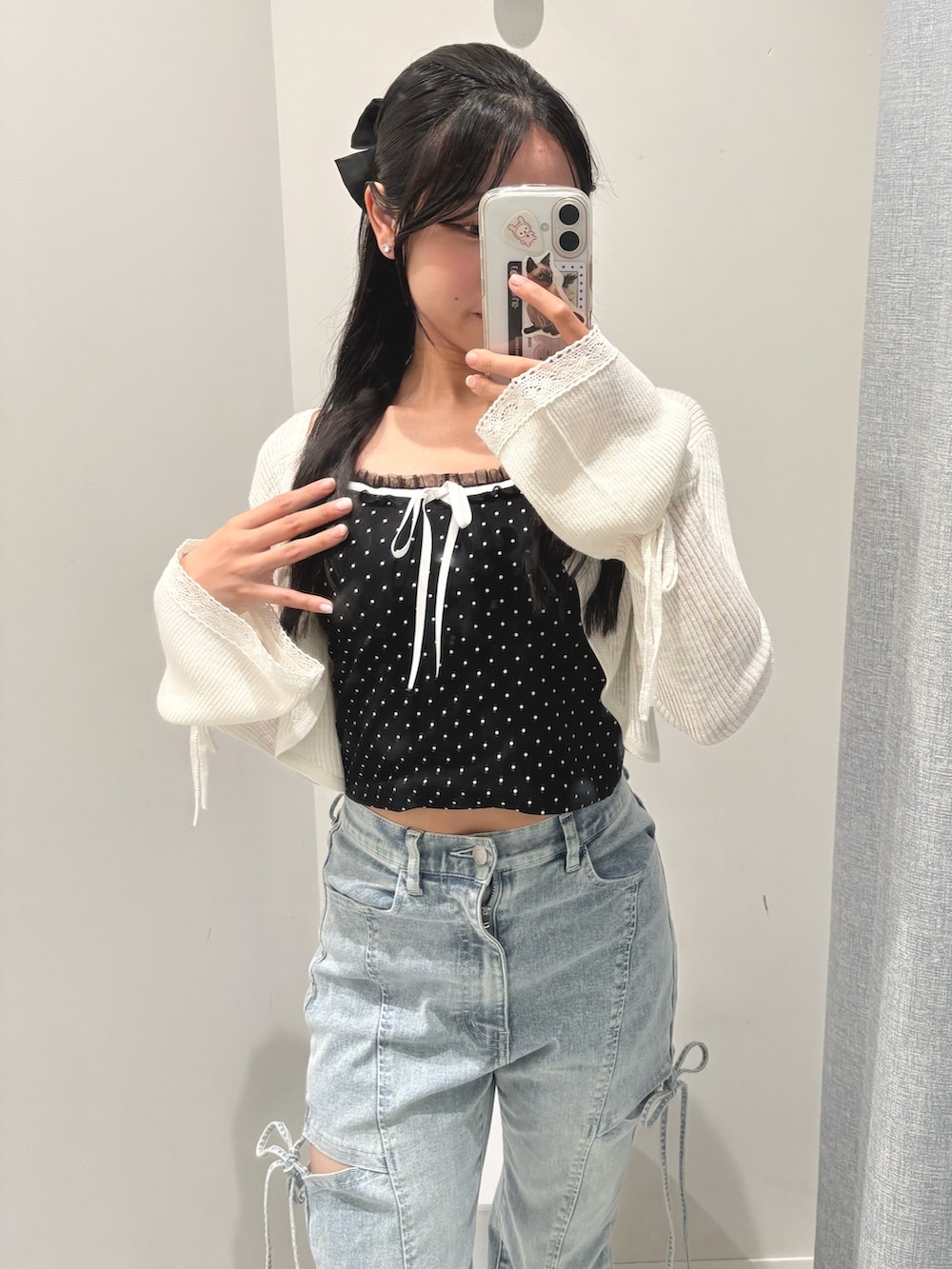 ブラック系のキャミソール、ホワイト系のカーディガン/ボレロ、ブルー系のデニムパンツを着用したレディースの夏コーディネートの3枚目の写真