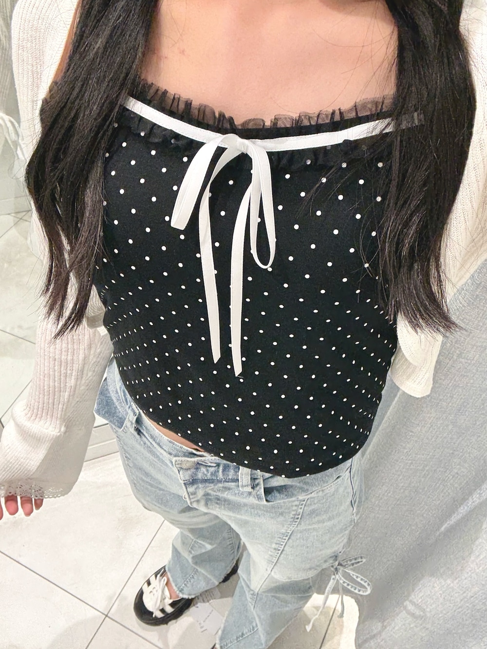 ブラック系のキャミソール、ホワイト系のカーディガン/ボレロ、ブルー系のデニムパンツを着用したレディースの夏コーディネートの4枚目の写真