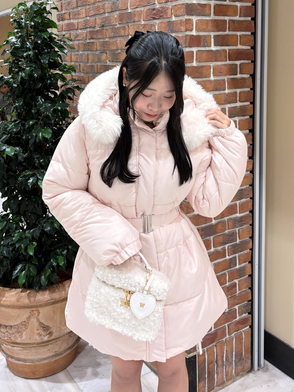 ピンク系のダウンジャケット/コート、ホワイト系のショルダーバッグ、ブラック系のブーツを着用したレディースの冬コーディネートの4枚目の写真