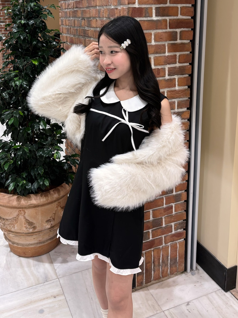 ブラック系のドレス、ホワイト系のその他アウター、ブラック系のスニーカーを着用したレディースの冬コーディネートの3枚目の写真