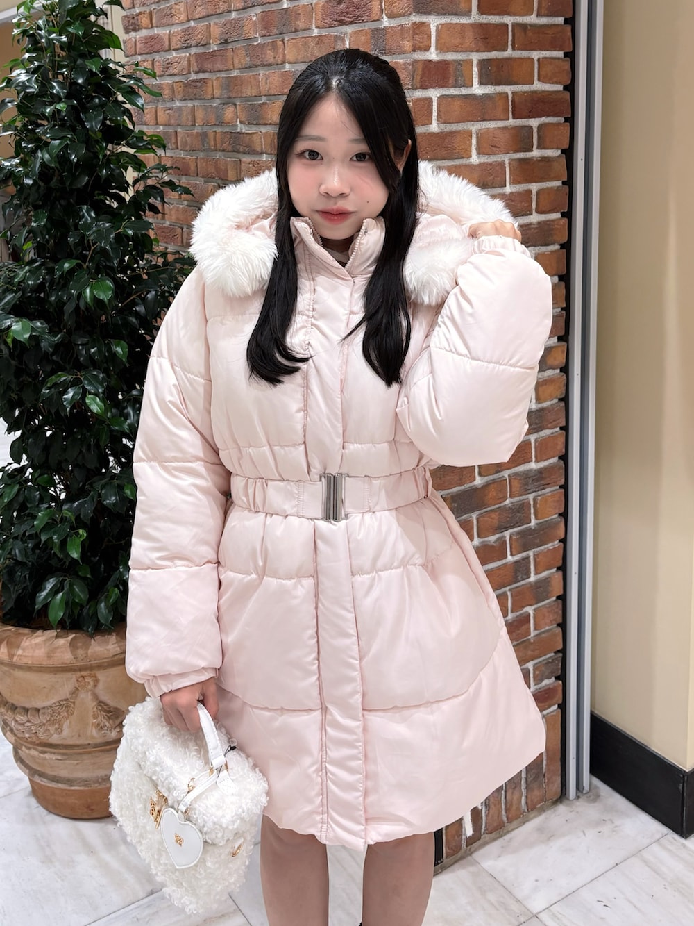 ピンク系のダウンジャケット/コート、ホワイト系のショルダーバッグ、ブラック系のブーツを着用したレディースの冬コーディネートの3枚目の写真