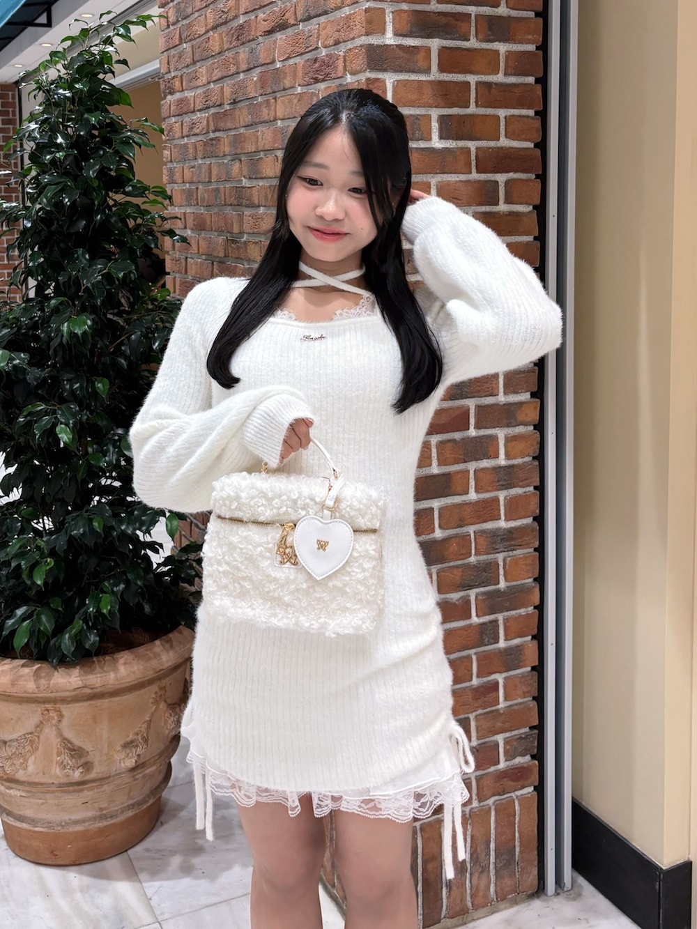 ホワイト系のワンピース、ホワイト系のショルダーバッグ、ブラック系のブーツを着用したレディースの冬コーディネートの2枚目の写真