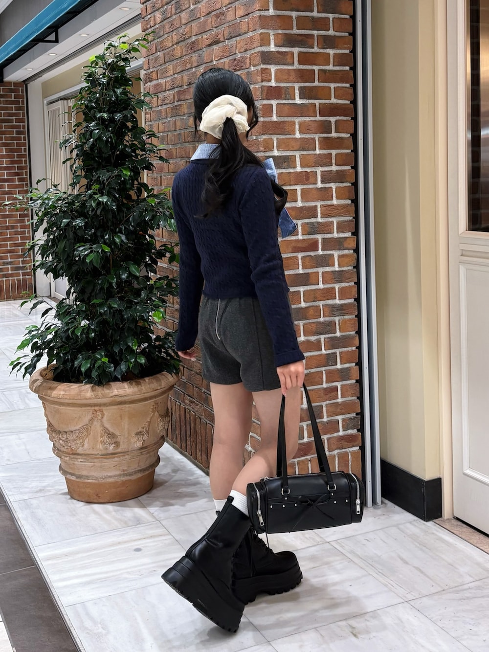 ブルー系のニット/セーター、グレー系のその他パンツ、ブラック系のトートバッグを着用したレディースの冬コーディネートの3枚目の写真