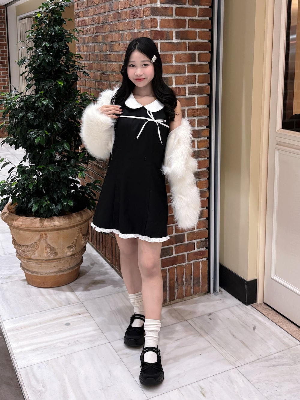 ブラック系のドレス、ホワイト系のその他アウター、ブラック系のスニーカーを着用したレディースの冬コーディネートの2枚目の写真