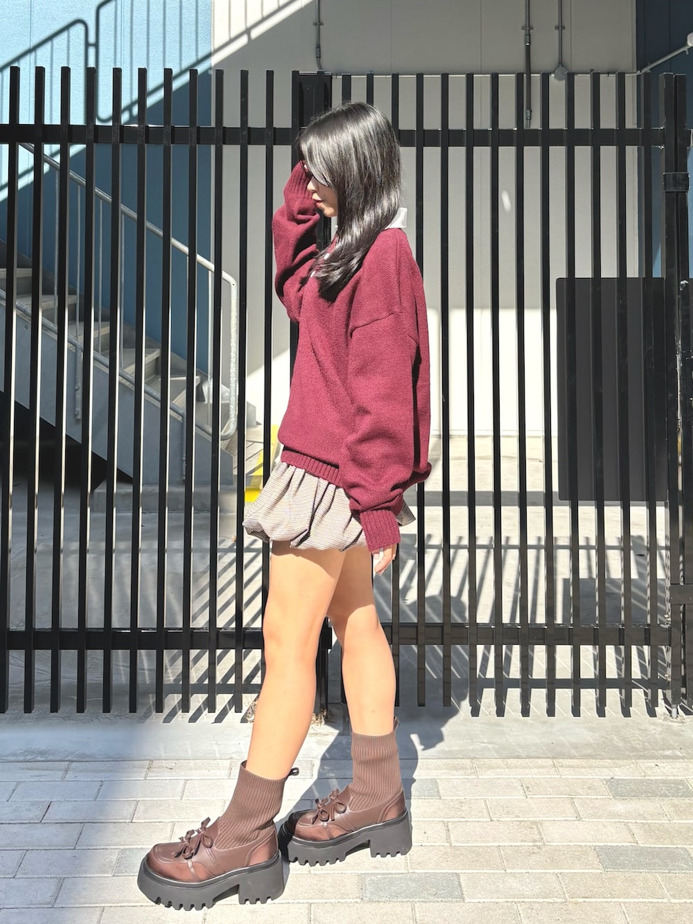 レッド系のニット/セーター、その他のスカート、ブラウン系のブーツを着用したレディースの秋コーディネートの2枚目の写真