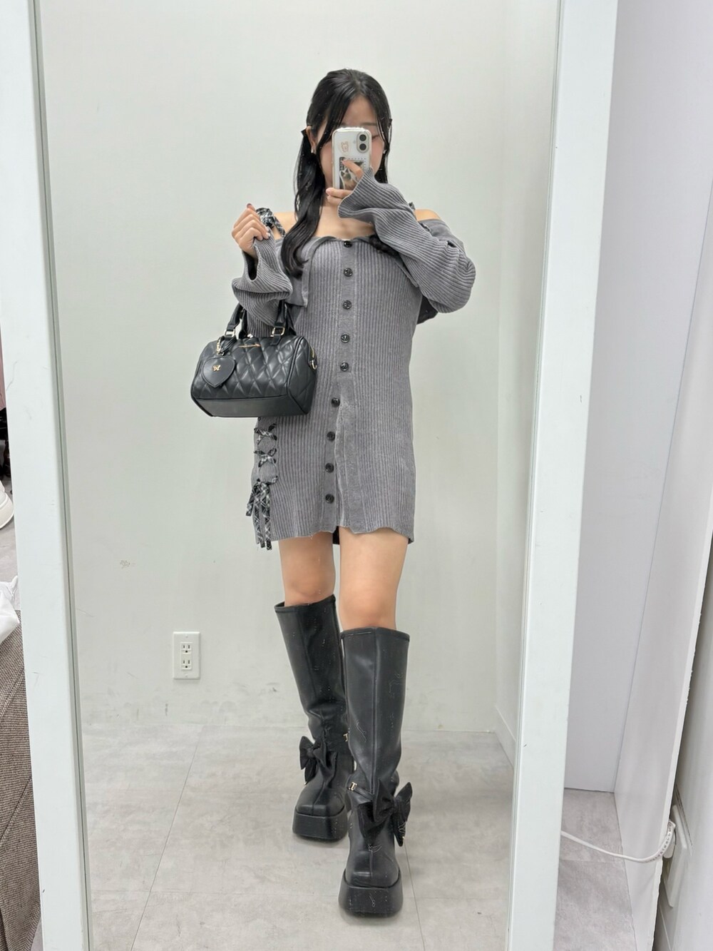 グレー系のワンピース、ブラック系のボストンバッグ、ブラック系のブーツを着用したレディースの夏コーディネートの2枚目の写真