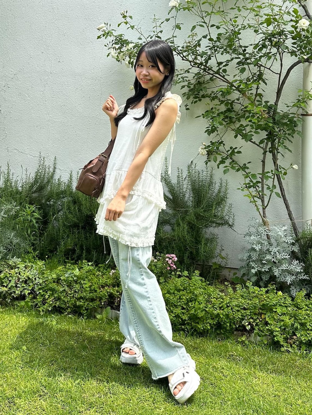 ホワイト系のキャミソール、ブルー系のデニムパンツ、ブラウン系のショルダーバッグを着用したレディースの夏コーディネートの2枚目の写真