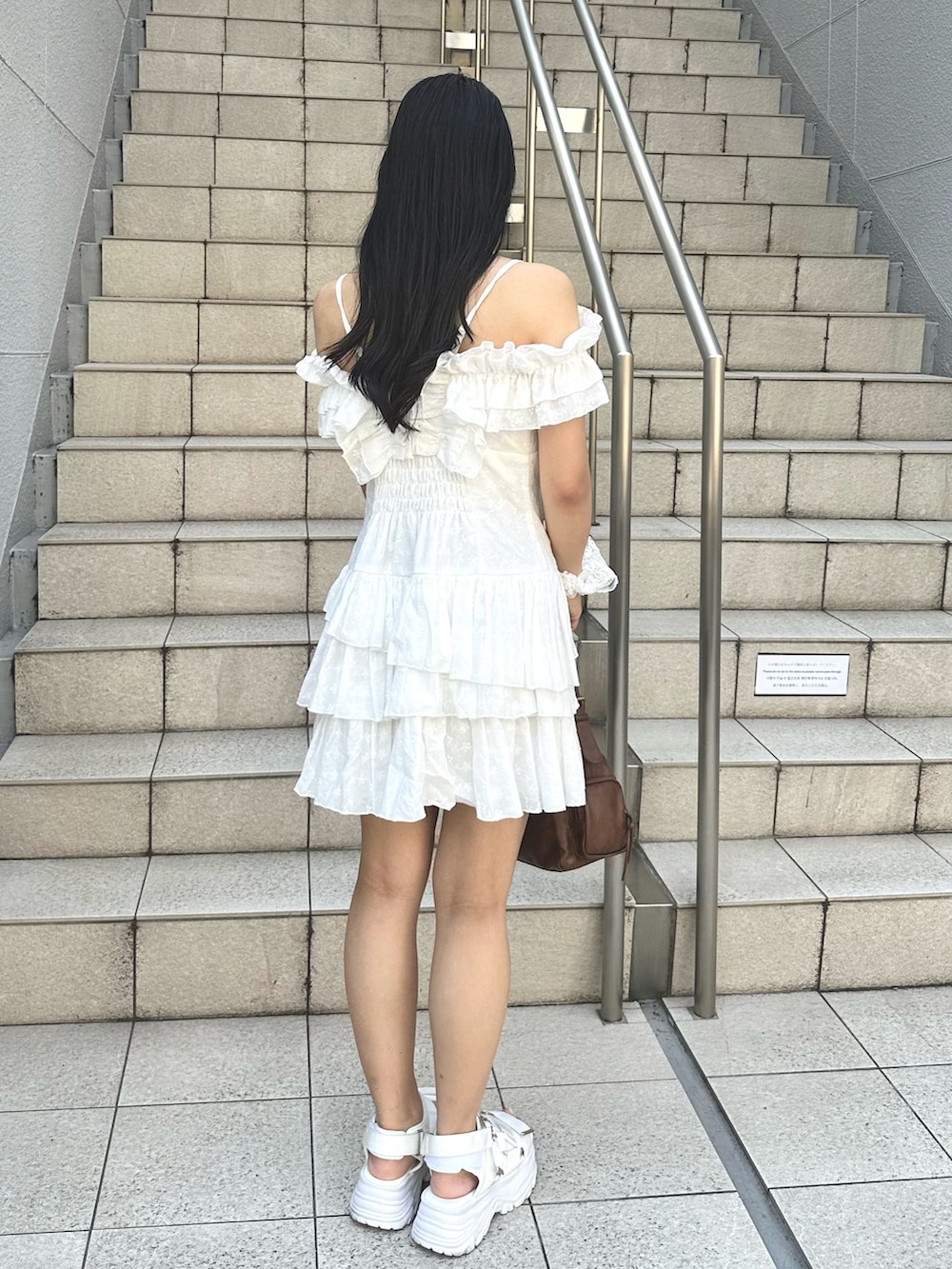 ホワイト系のワンピース、ホワイト系のサンダル、ブラウン系のショルダーバッグを着用したレディースの夏コーディネートの3枚目の写真