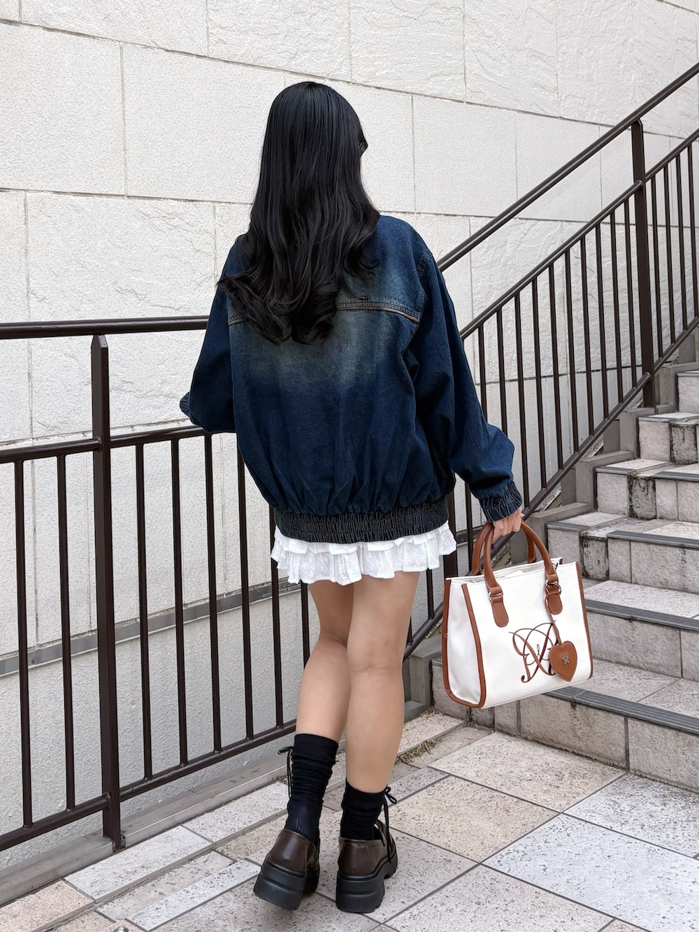 ブルー系のブルゾン、ブラウン系のトートバッグ、ホワイト系のスカートを着用したレディースの冬コーディネートの4枚目の写真