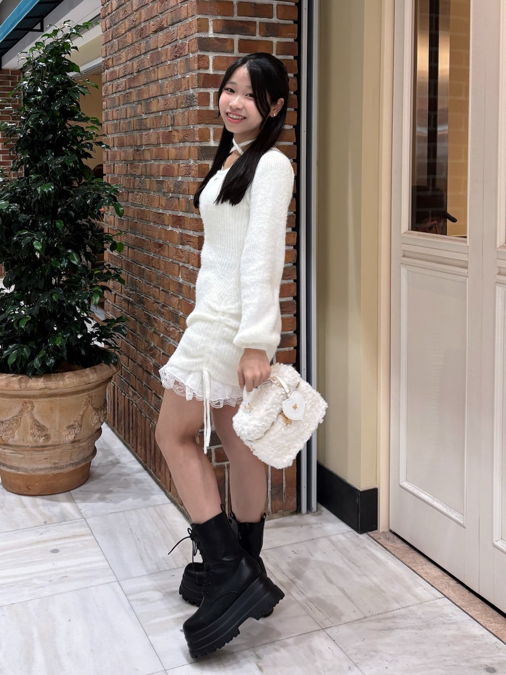 ホワイト系のワンピース、ホワイト系のショルダーバッグ、ブラック系のブーツを着用したレディースの冬コーディネートの4枚目の写真