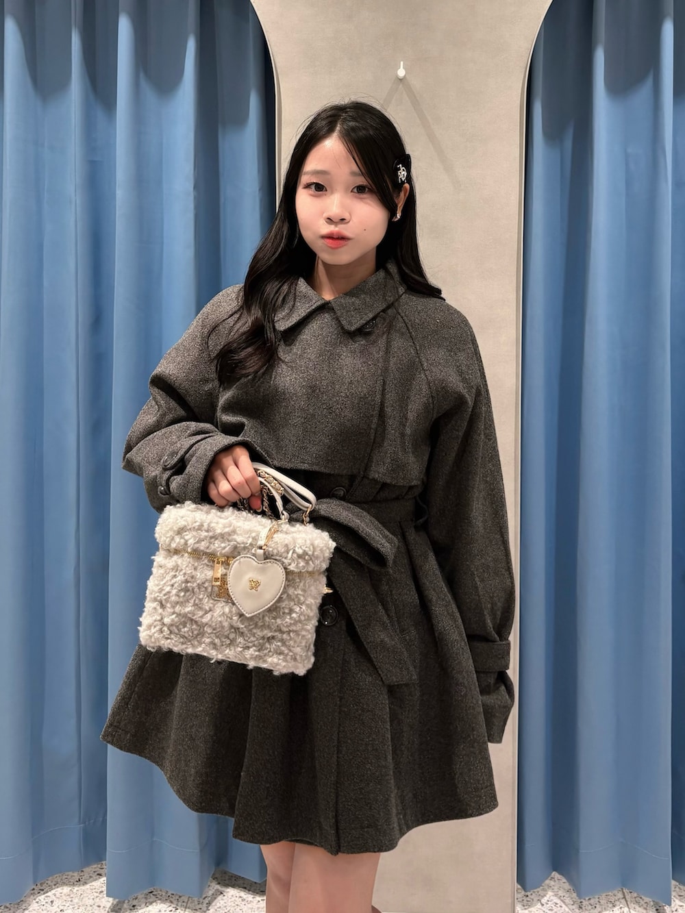 グレー系のステンカラーコート、グレー系のショルダーバッグ、ブラック系のブーツを着用したレディースの冬コーディネートの4枚目の写真