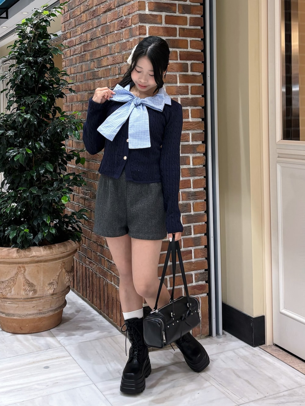 ブルー系のニット/セーター、グレー系のその他パンツ、ブラック系のトートバッグを着用したレディースの冬コーディネートの4枚目の写真