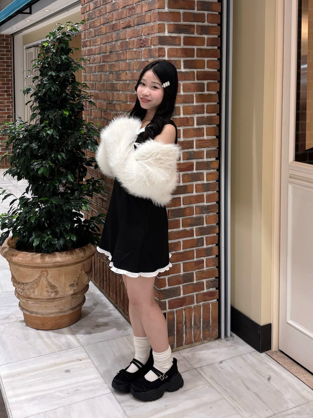 ブラック系のドレス、ホワイト系のその他アウター、ブラック系のスニーカーを着用したレディースの冬コーディネートの4枚目の写真