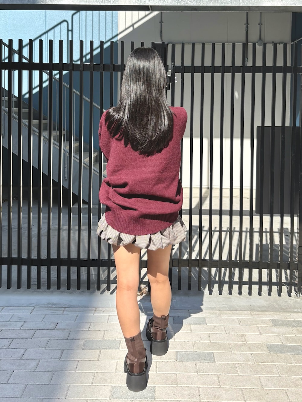 レッド系のニット/セーター、その他のスカート、ブラウン系のブーツを着用したレディースの秋コーディネートの3枚目の写真