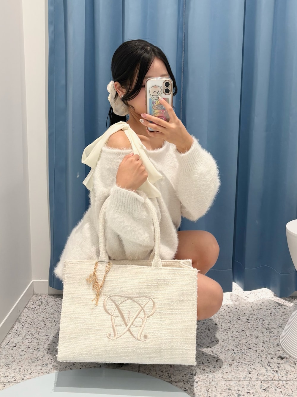 ホワイト系のワンピース、グレー系のスカート、ホワイト系のトートバッグを着用したレディースの冬コーディネートの2枚目の写真