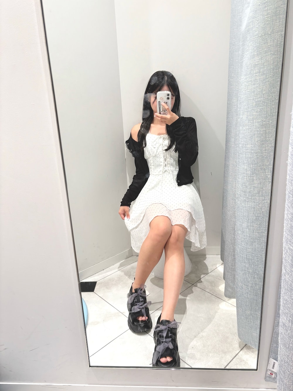 ブラック系のカーディガン/ボレロ、ホワイト系のワンピース、ブラック系のデニムパンツを着用したレディースの夏コーディネートの2枚目の写真