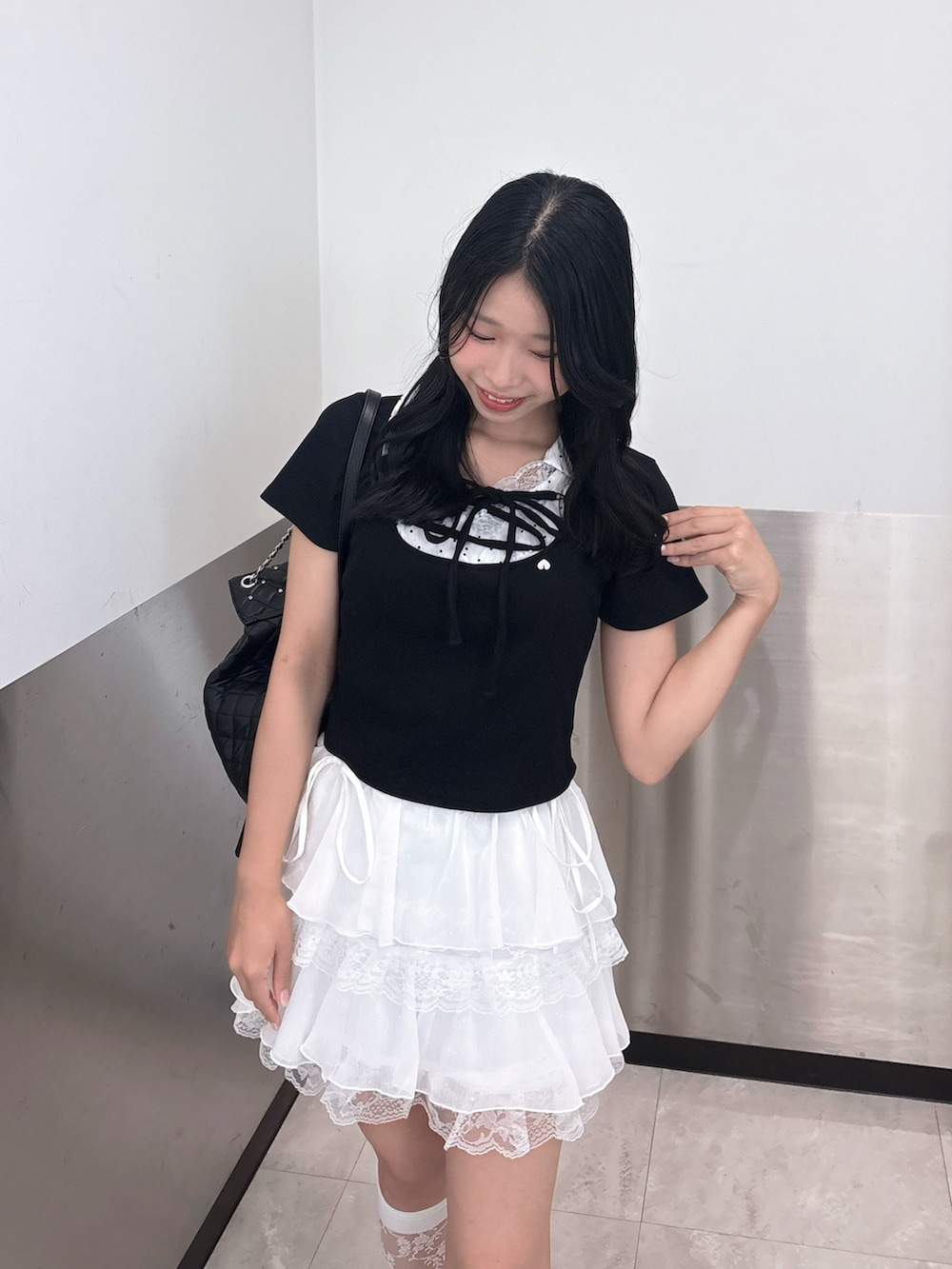 ブラック系のTシャツ/カットソー、ブラック系のバックパック/リュック、ホワイト系のスカートを着用したレディースの夏コーディネートの2枚目の写真