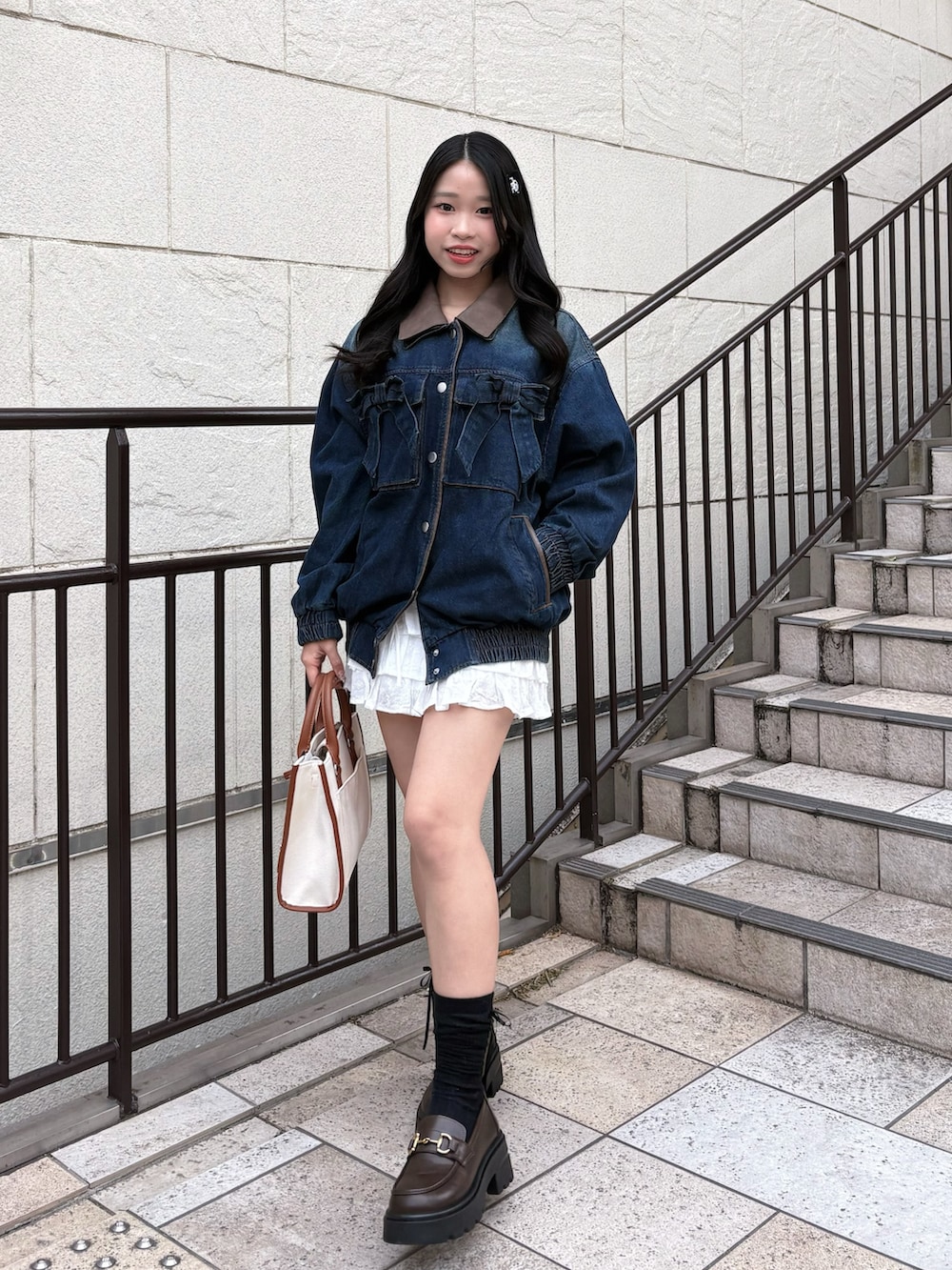 ブルー系のブルゾン、ブラウン系のトートバッグ、ホワイト系のスカートを着用したレディースの冬コーディネートの2枚目の写真