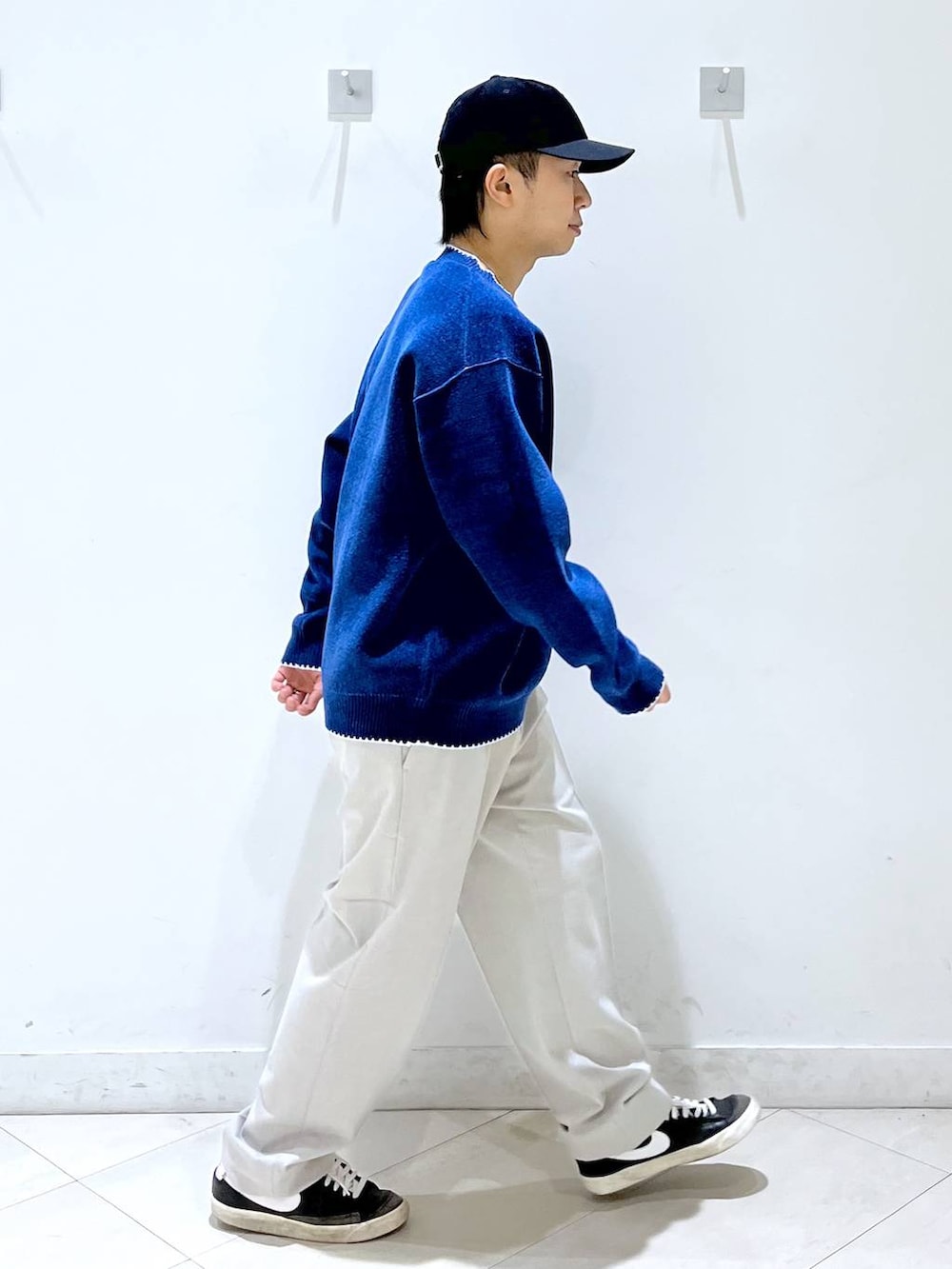 ベージュ系のその他パンツ、ブルー系のニット/セーター、ブルー系のキャップを着用したメンズの秋コーディネートの2枚目の写真