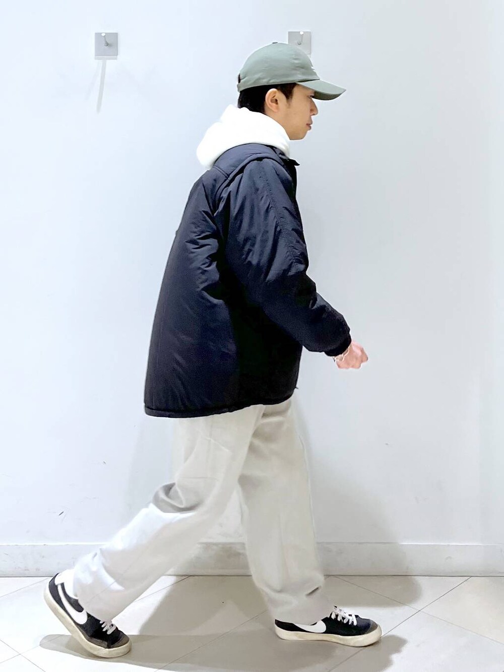 ブラック系のブルゾン、ベージュ系のその他パンツ、ホワイト系のパーカーを着用したメンズの冬コーディネートの2枚目の写真