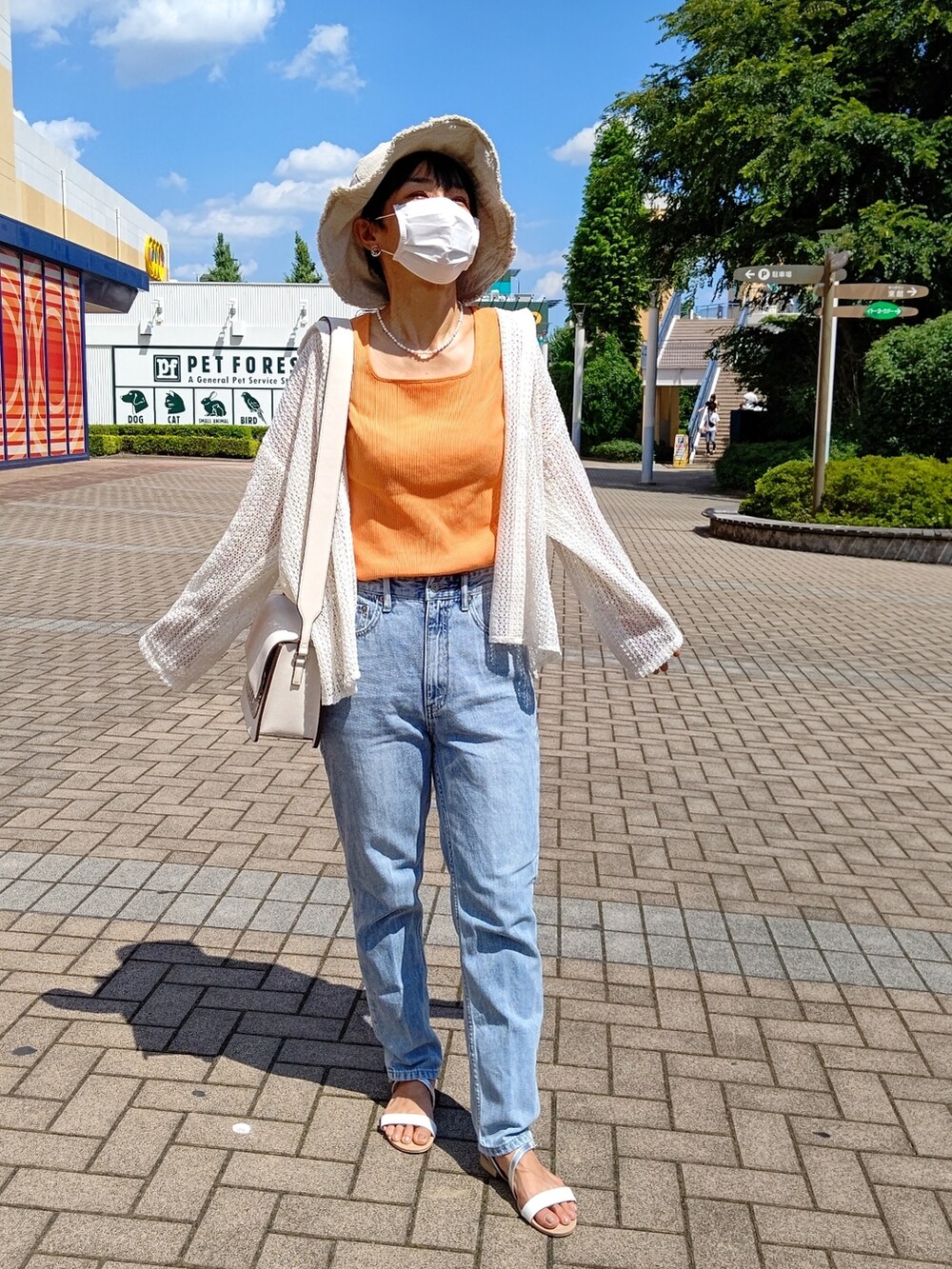 オレンジ系のタンクトップ、ホワイト系のシャツ/ブラウス、ブルー系のデニムパンツを着用したレディースの夏コーディネートの3枚目の写真