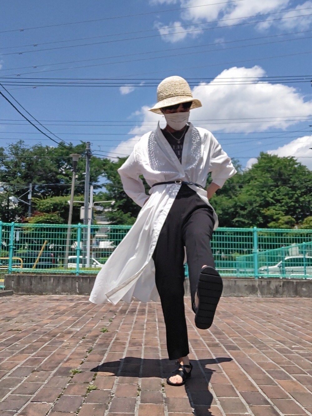 ホワイト系のワンピース、ブラック系のスラックス、ブラック系のサンダルを着用したレディースの夏コーディネートの2枚目の写真