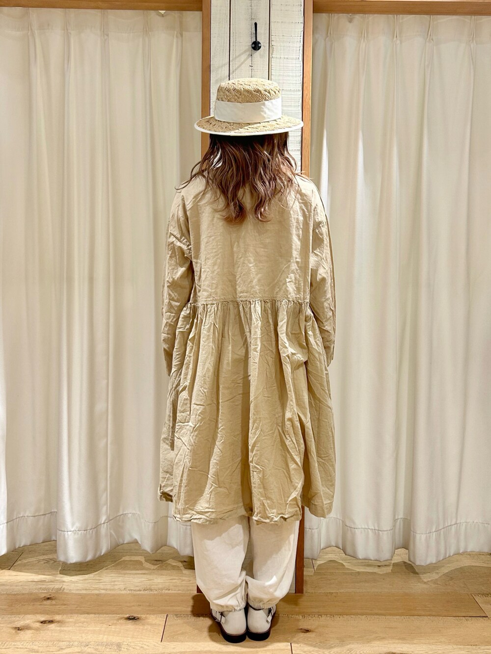 ベージュ系のチュニック、ホワイト系のハットを着用したレディースの春コーディネートの3枚目の写真