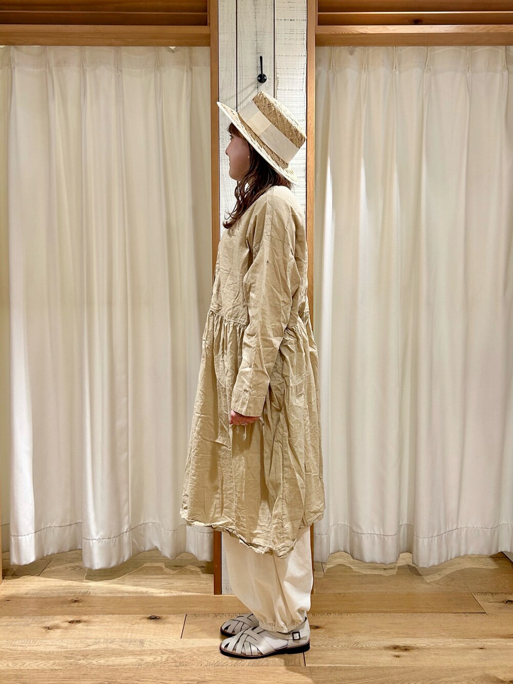 ベージュ系のチュニック、ホワイト系のハットを着用したレディースの春コーディネートの2枚目の写真