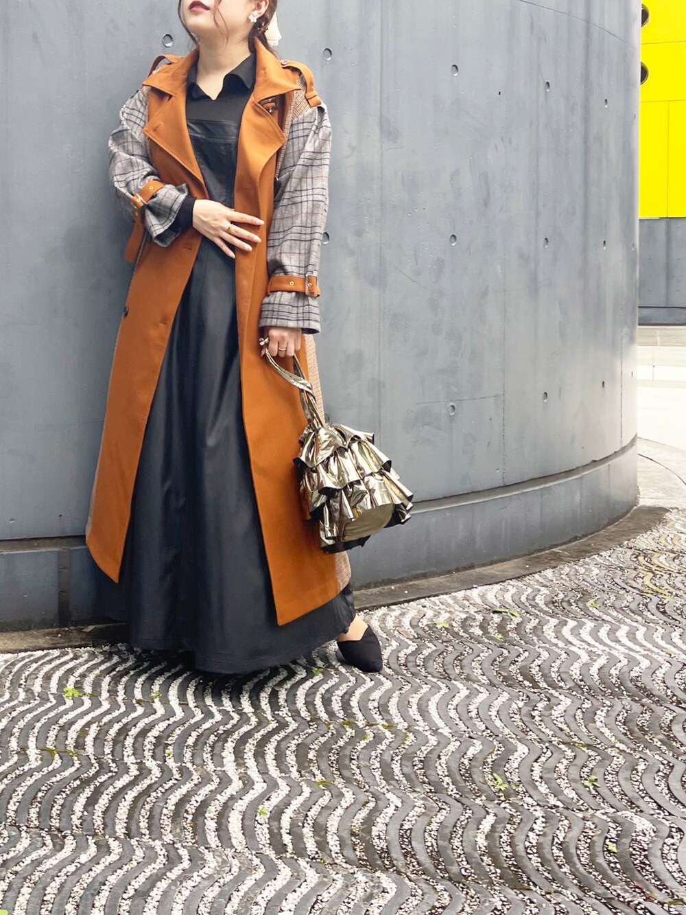 ゴールド系のバッグ、ブラック系のジャンパースカート、ブラウン系のジャケット/アウターを着用したレディースの秋コーディネートの2枚目の写真