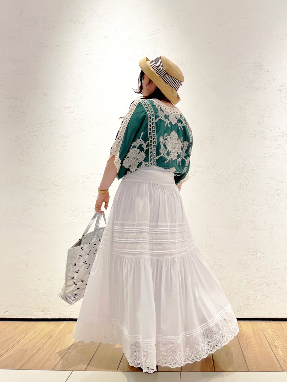 シルバー系のトートバッグ、ブラック系のサンダル、ホワイト系のスカートを着用したレディースの春コーディネートの2枚目の写真